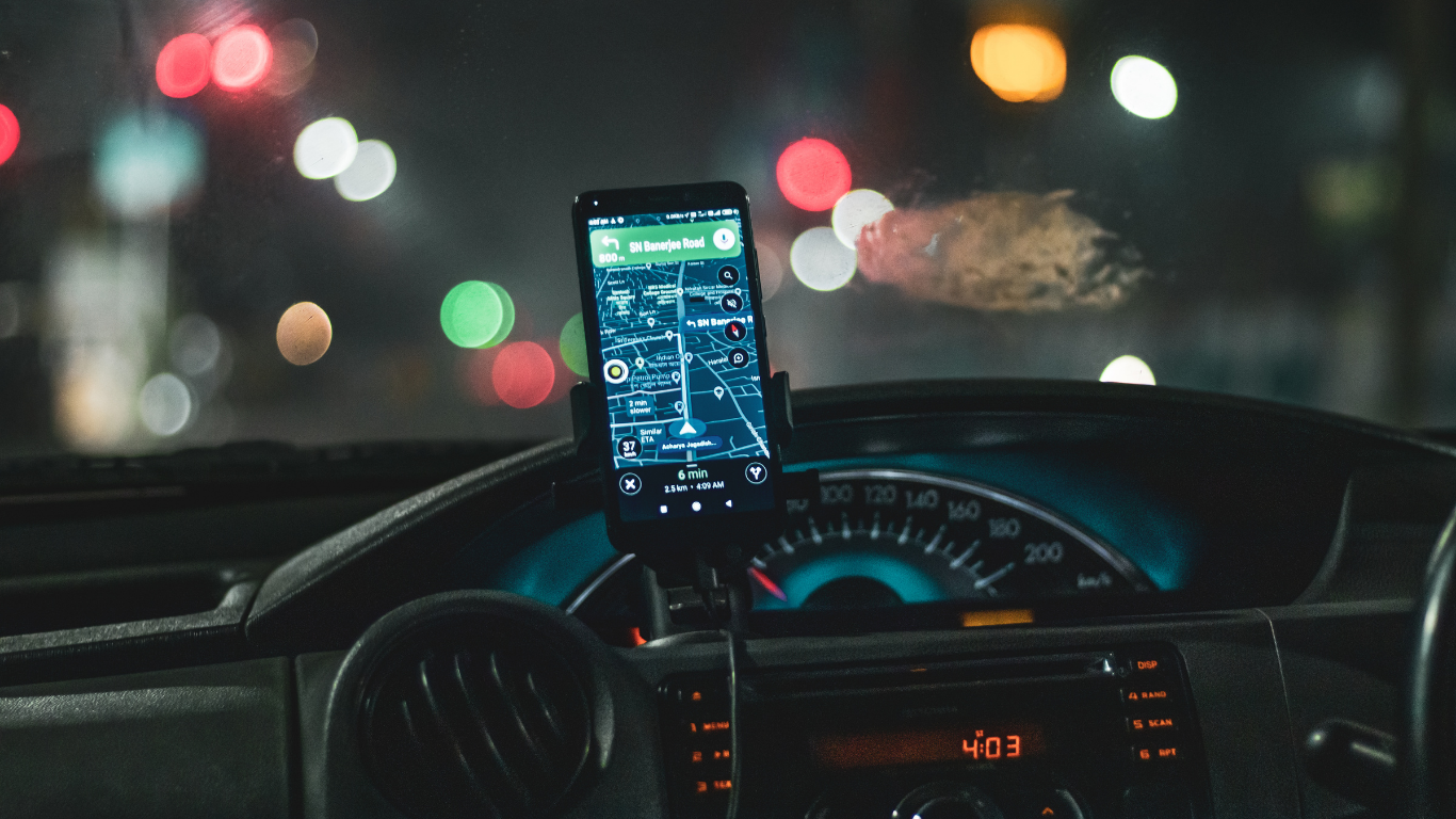 Motorista de aplicativo dirigindo em São Paulo com celular na mão, representando 10 erros que devem ser evitados em 2026.